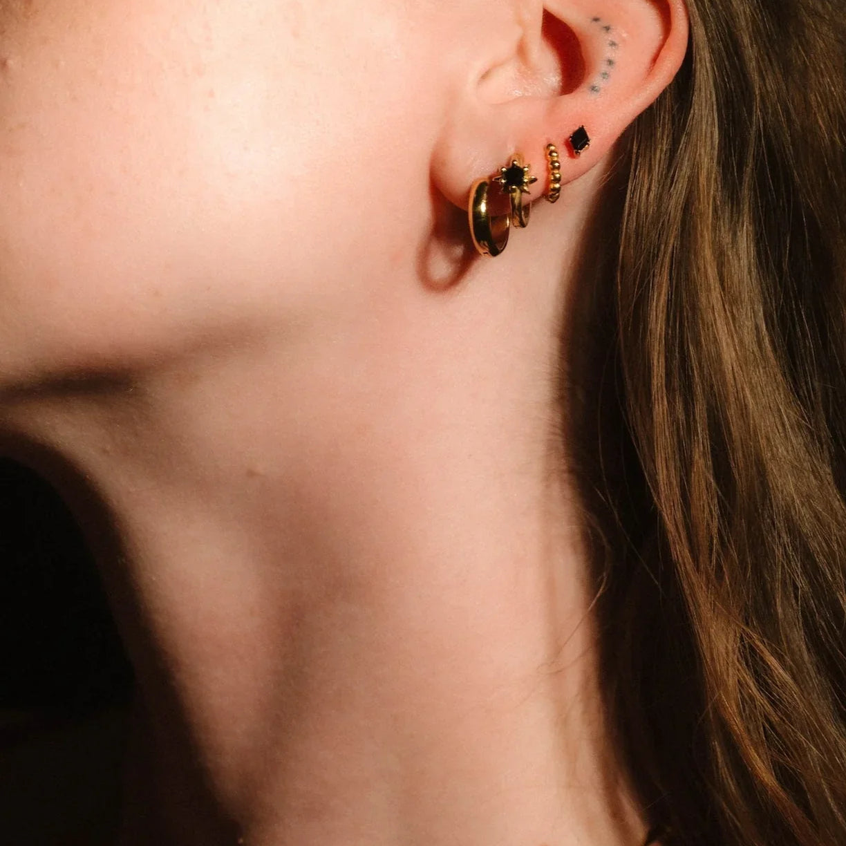 Profile headshot showcasing gold and black earrings
