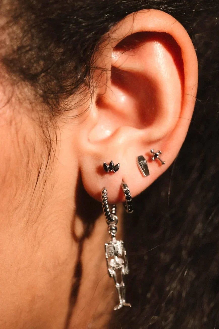 Close up photo of an ear wearing black and silver hoops and flat backs
