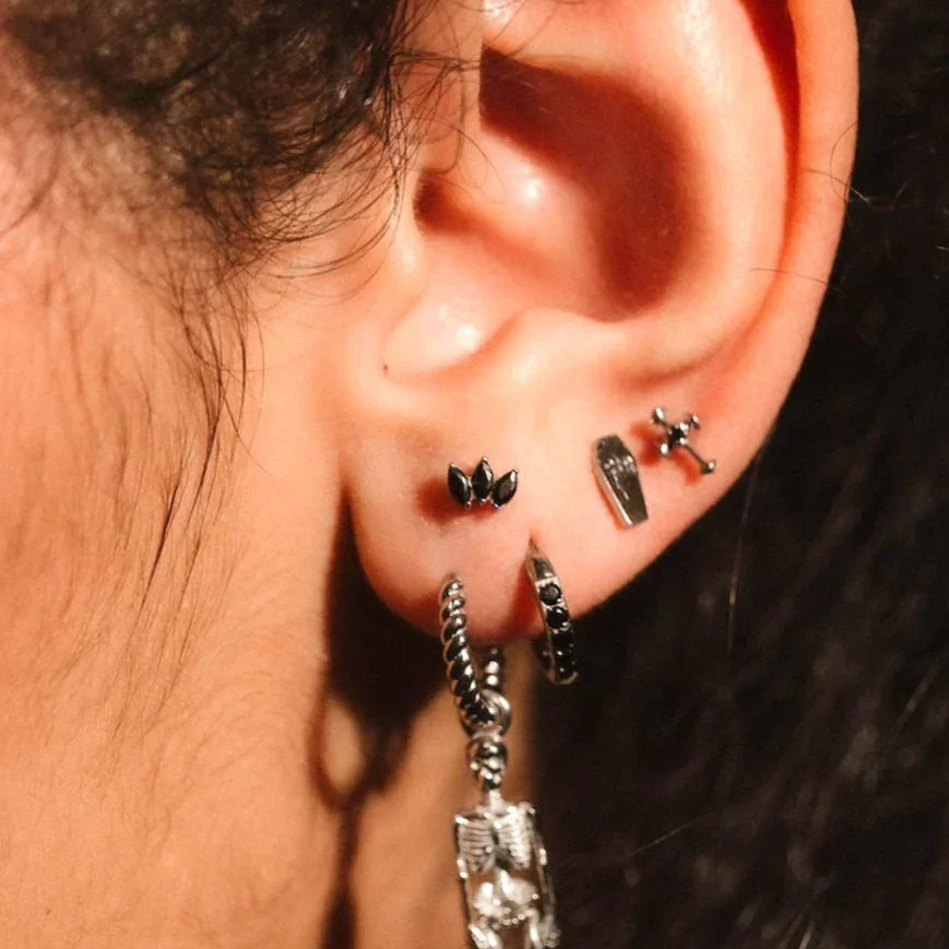 Close up photo of an ear wearing black and silver hoops and flat backs
