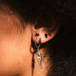 Close-up of an ear with a dangling earring against a dark background