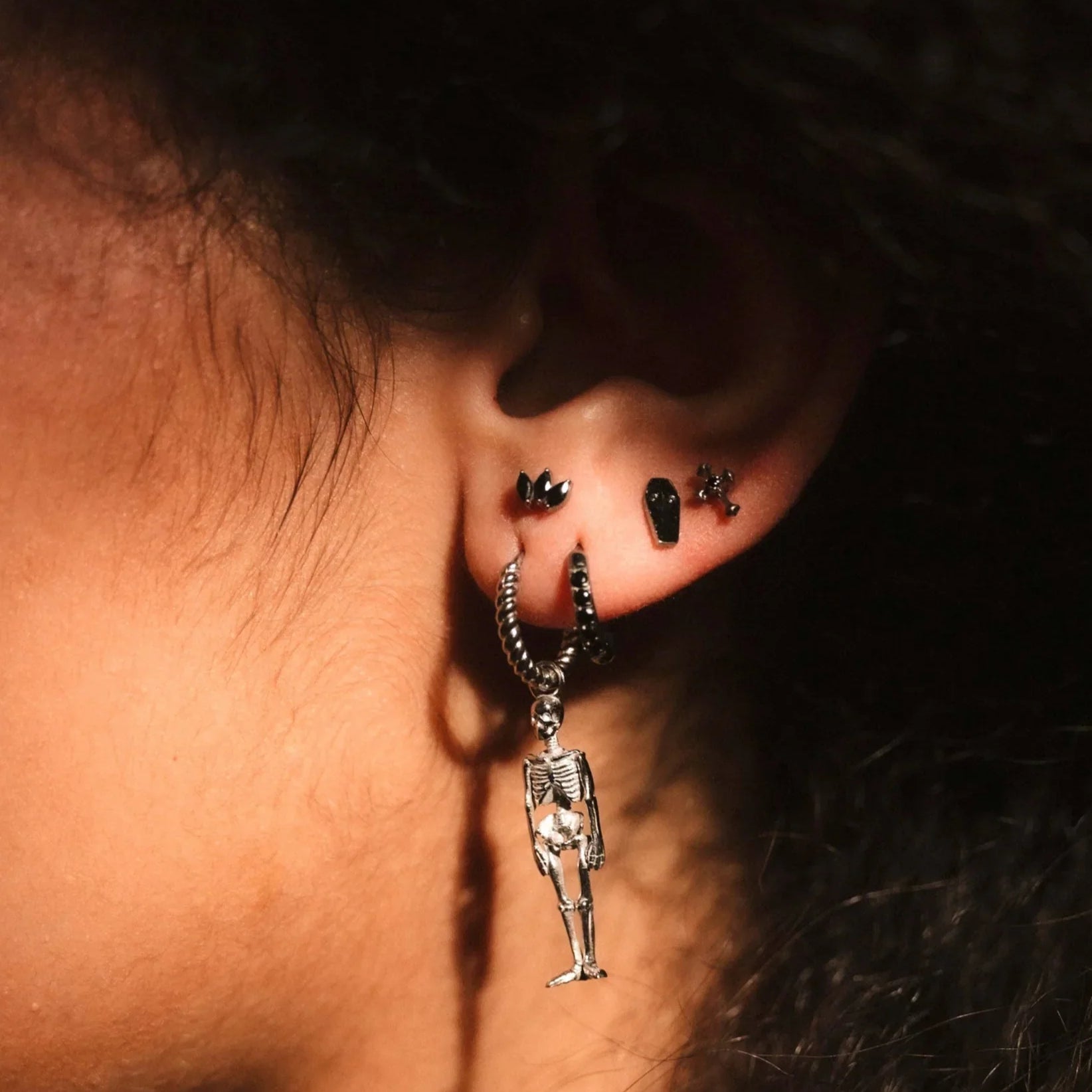 Close-up of an ear with a dangling earring against a dark background