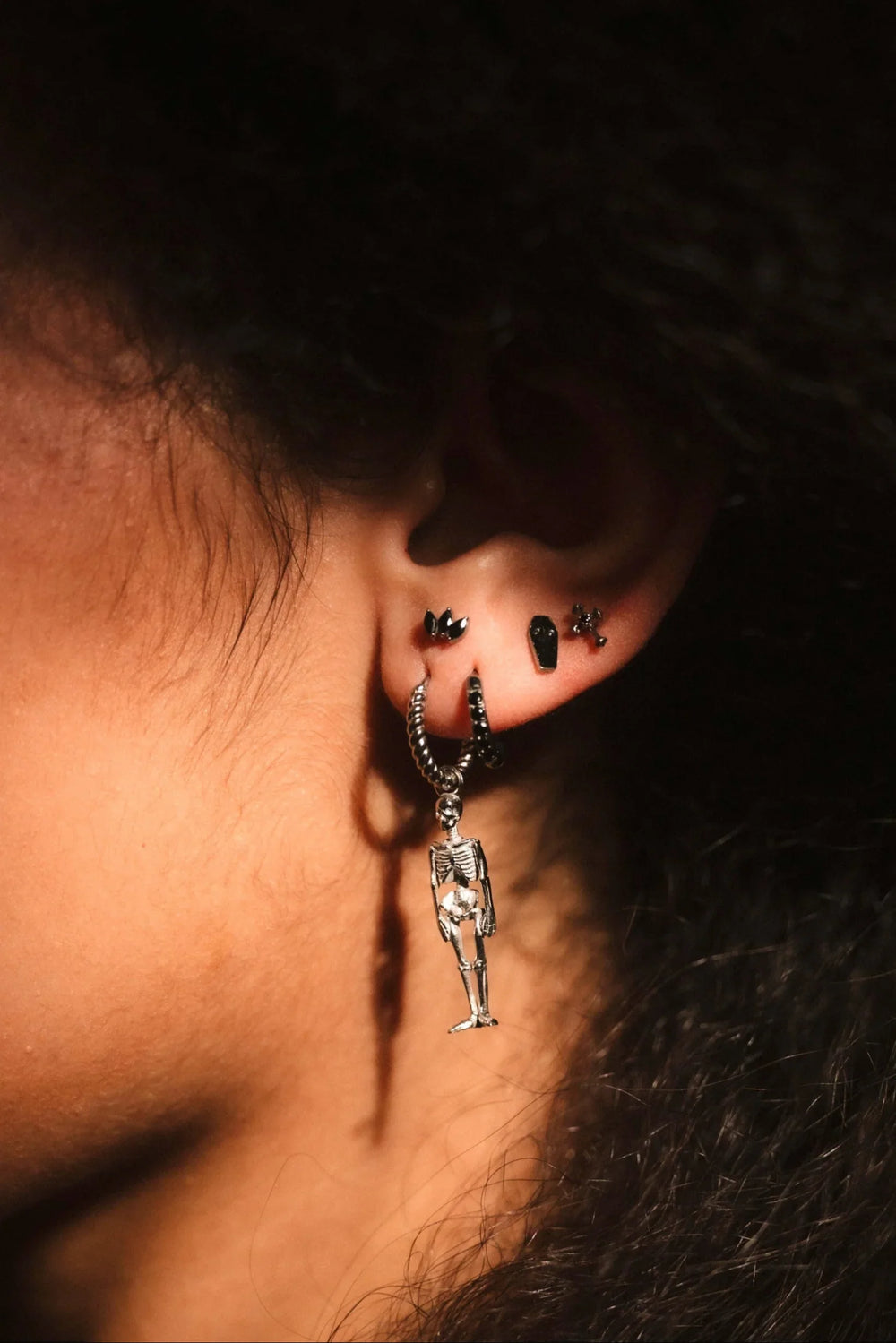 Close-up of an ear with a dangling earring against a dark background