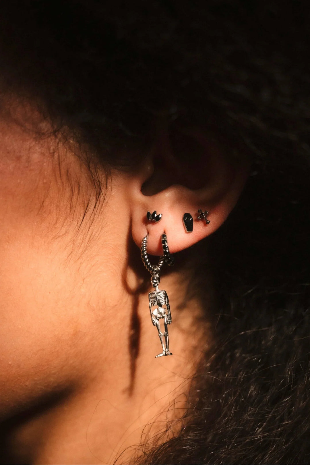 Close-up of an ear with a dangling earring against a dark background