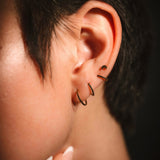 Close-up of an ear with a small hoop earring against a dark background