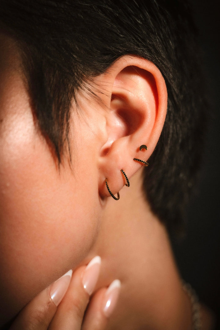 Close-up of an ear with a small hoop earring against a dark background