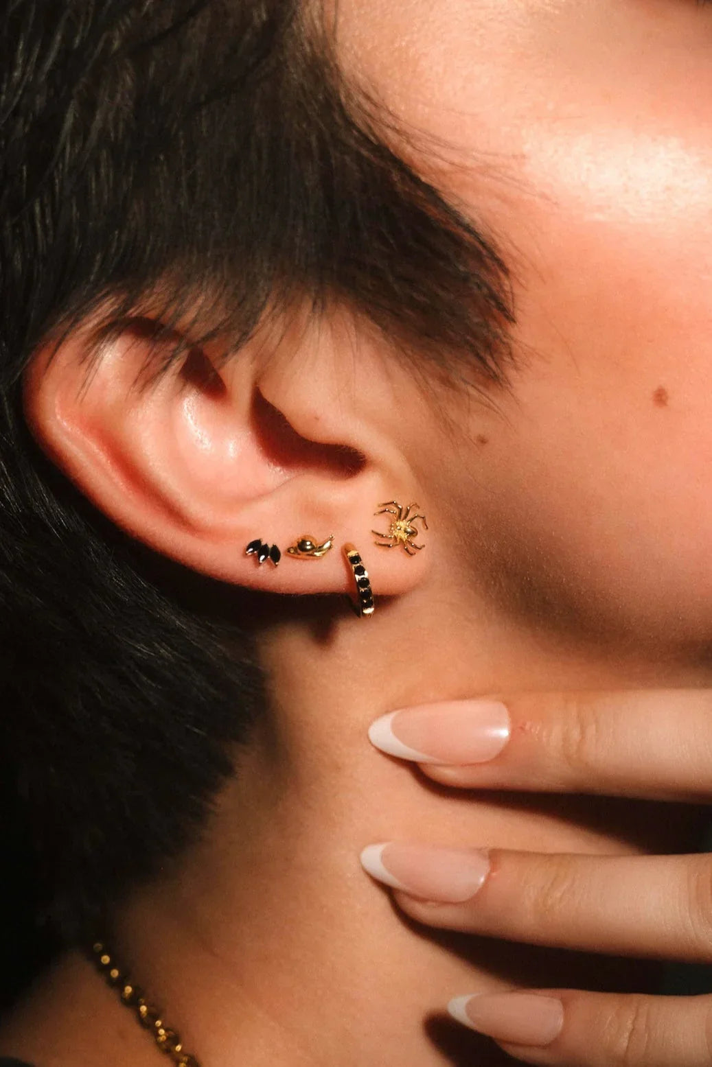 Close up of an ear with gold and black flat backs and hoops