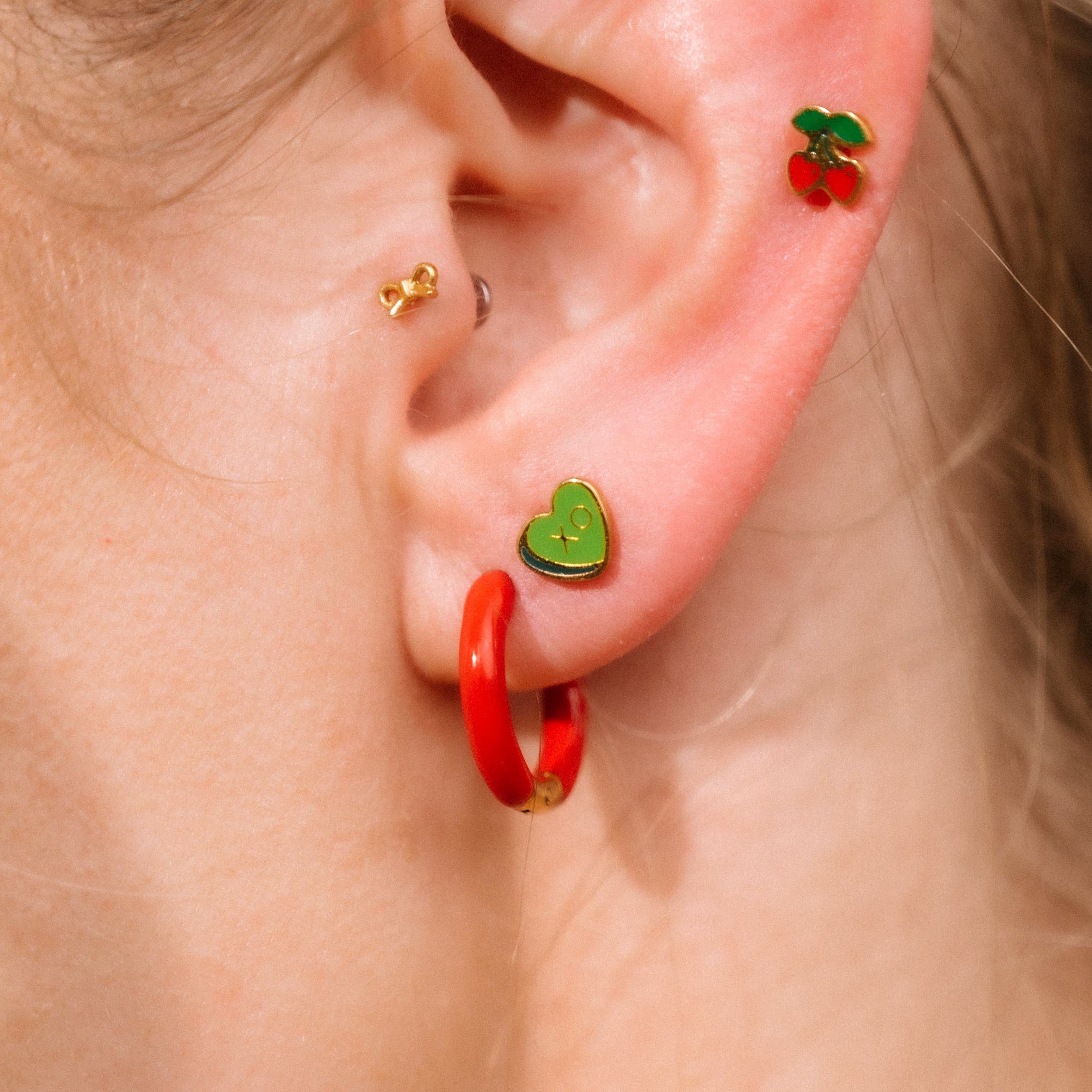 Close-up of an ear with colorful earrings on a neutral background