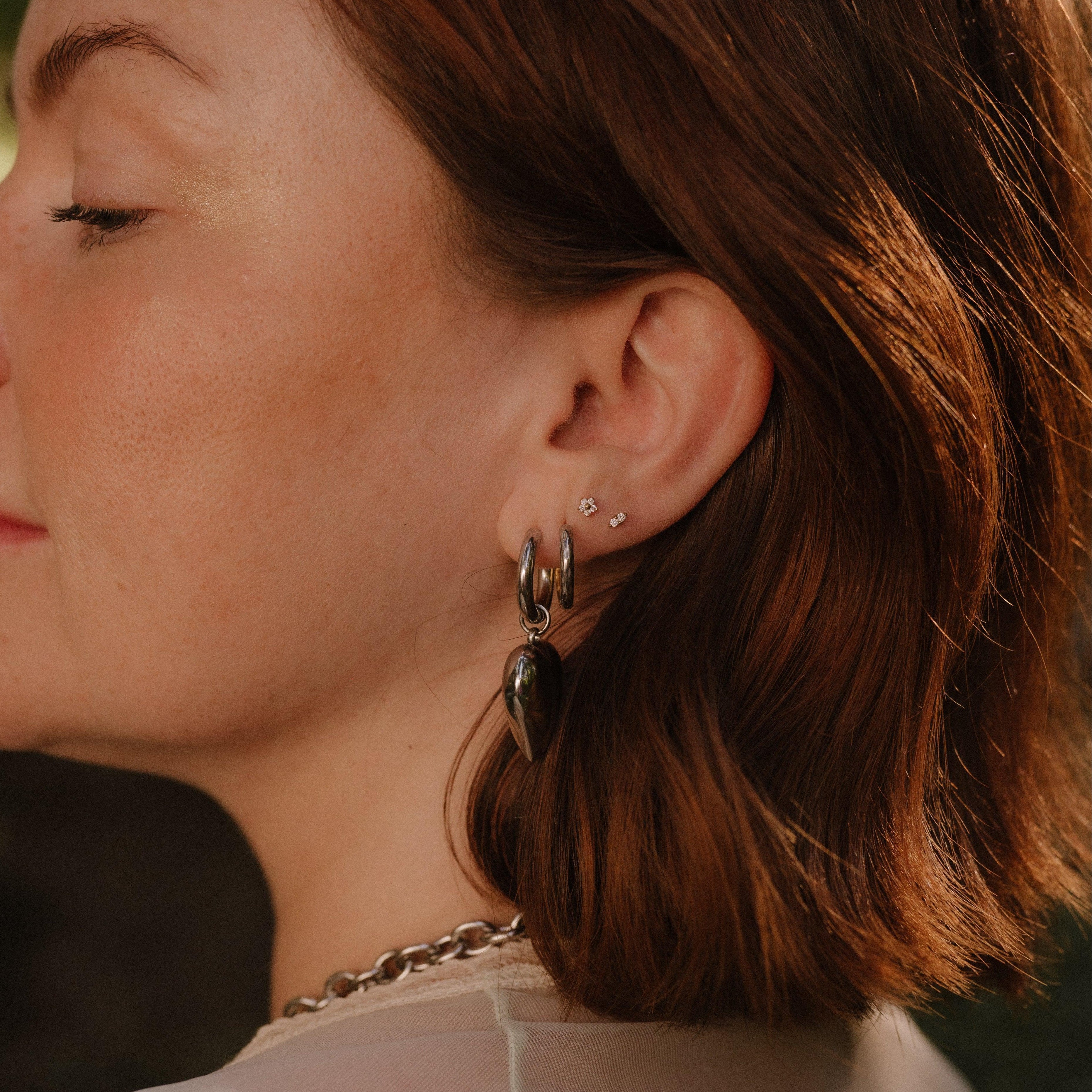 Close-up of a person wearing earrings with a blurred natural background