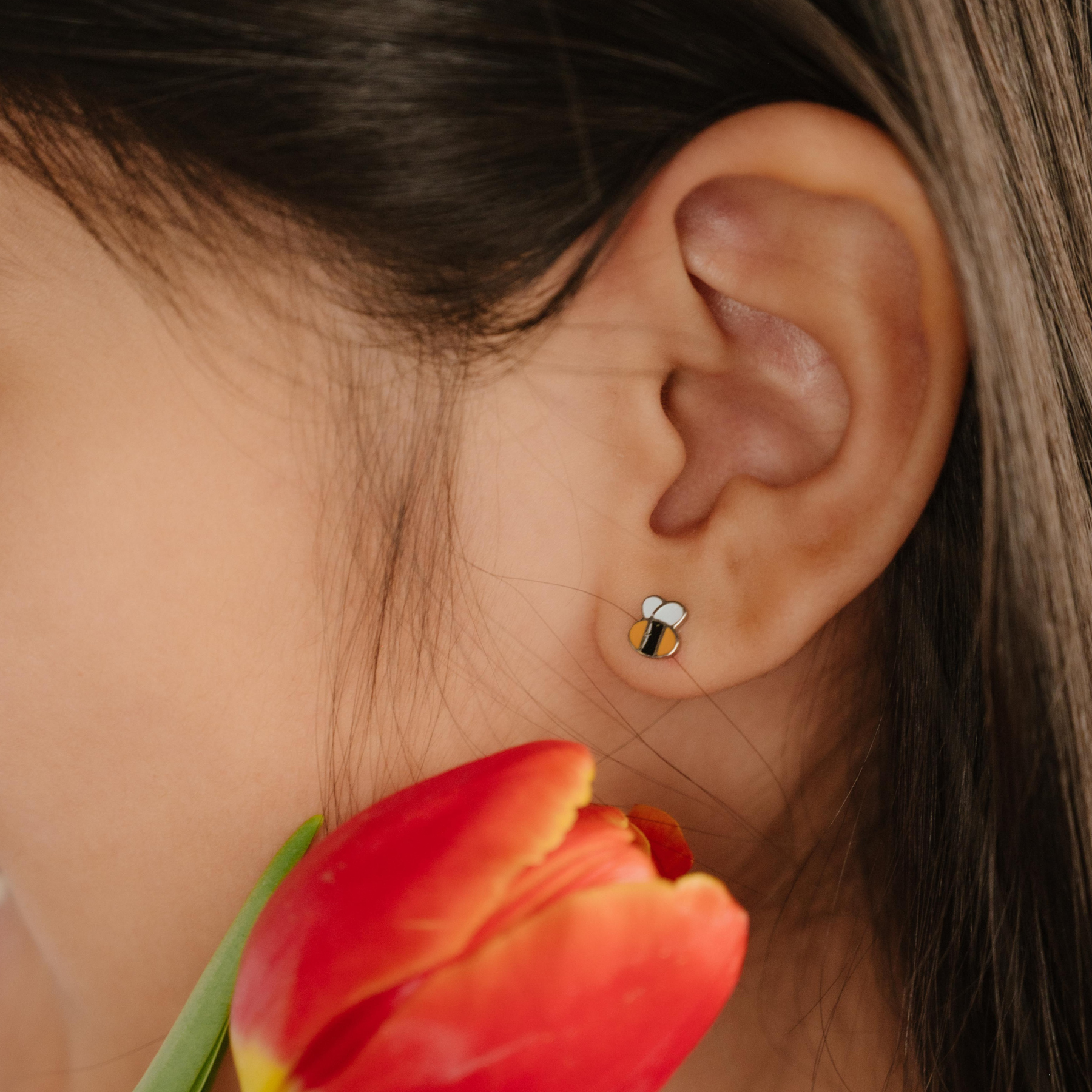 A close up of a bumblebee shaped flat back stud with yellow and black enamel and titanium metal.
