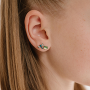 A close up of a dragonfly shaped flat back stud earring with blue enamel and titanium metal.
