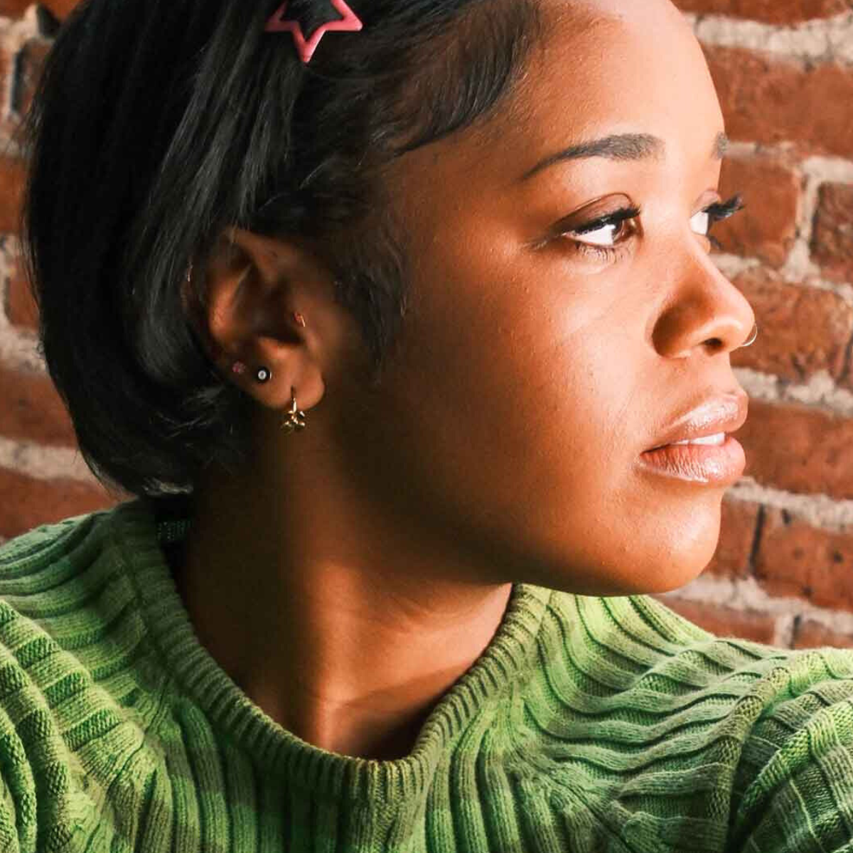 Photo of a model wearing multiple earrings, including a lightning bolt shaped flat back stud in hot pink enamel