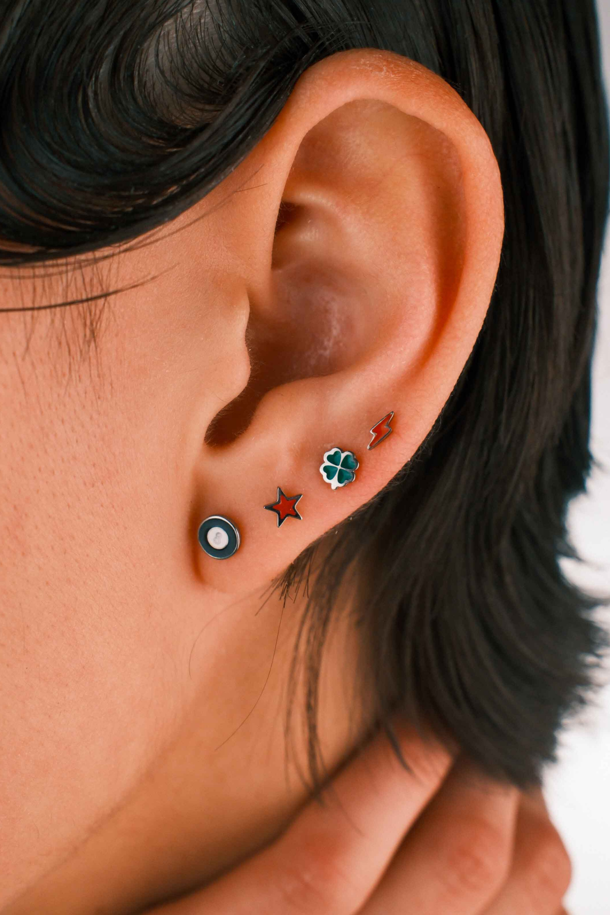 Close-up of an ear with multiple earrings against a blurred background