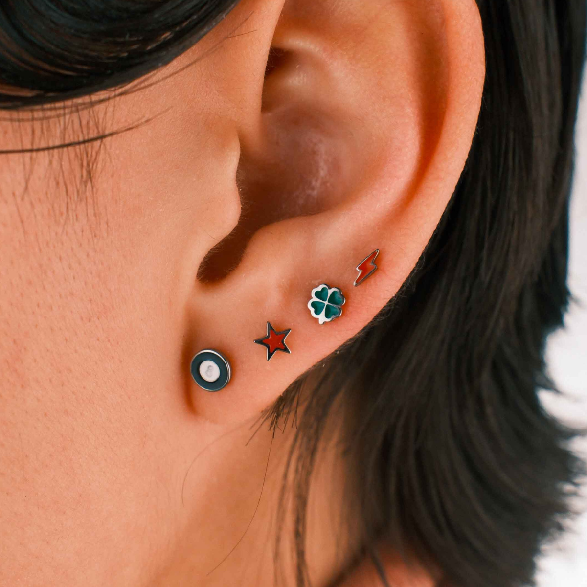 Close-up of an ear with multiple earrings against a blurred background