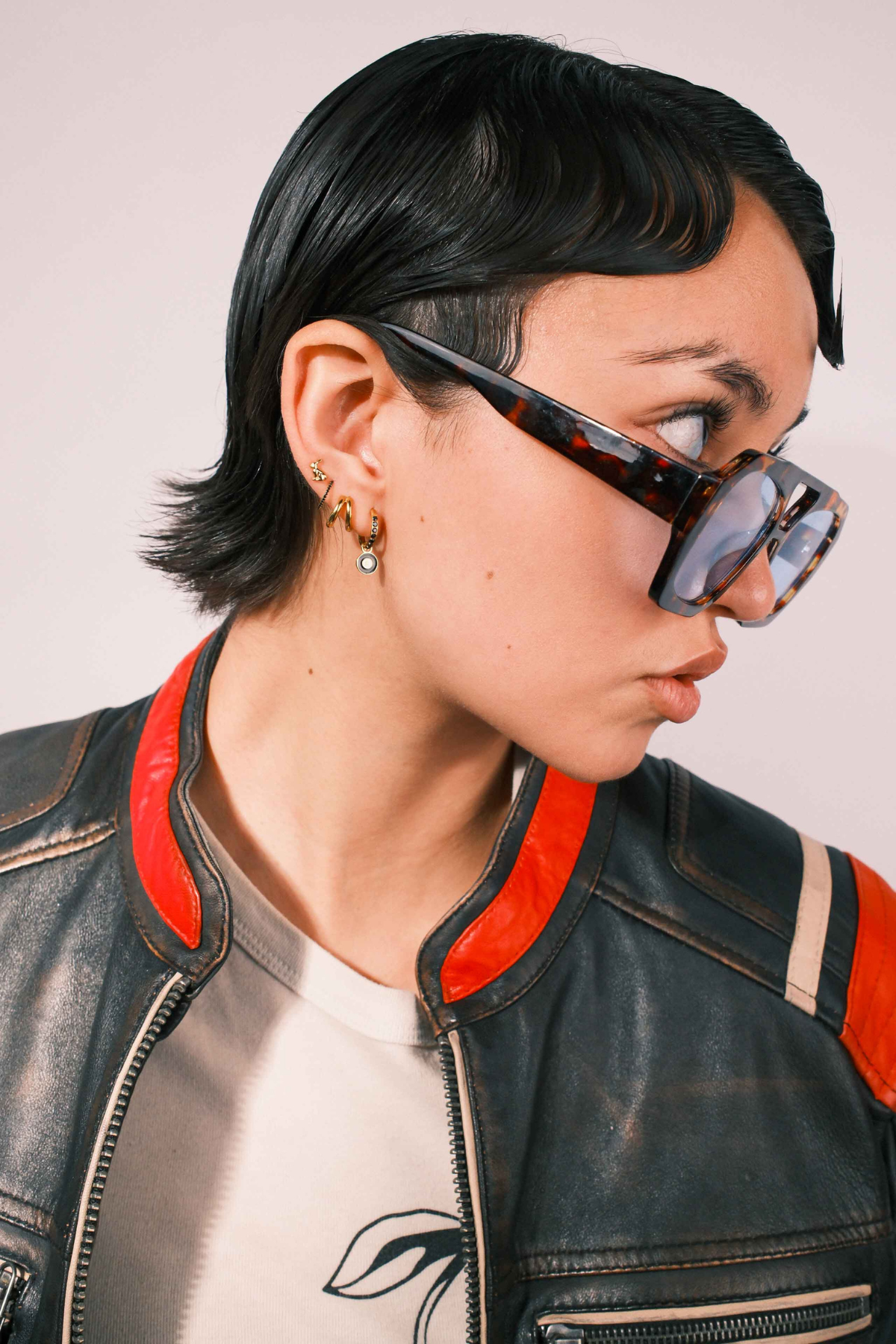 Close-up of an ear wearing gold and black earrings with a plain background