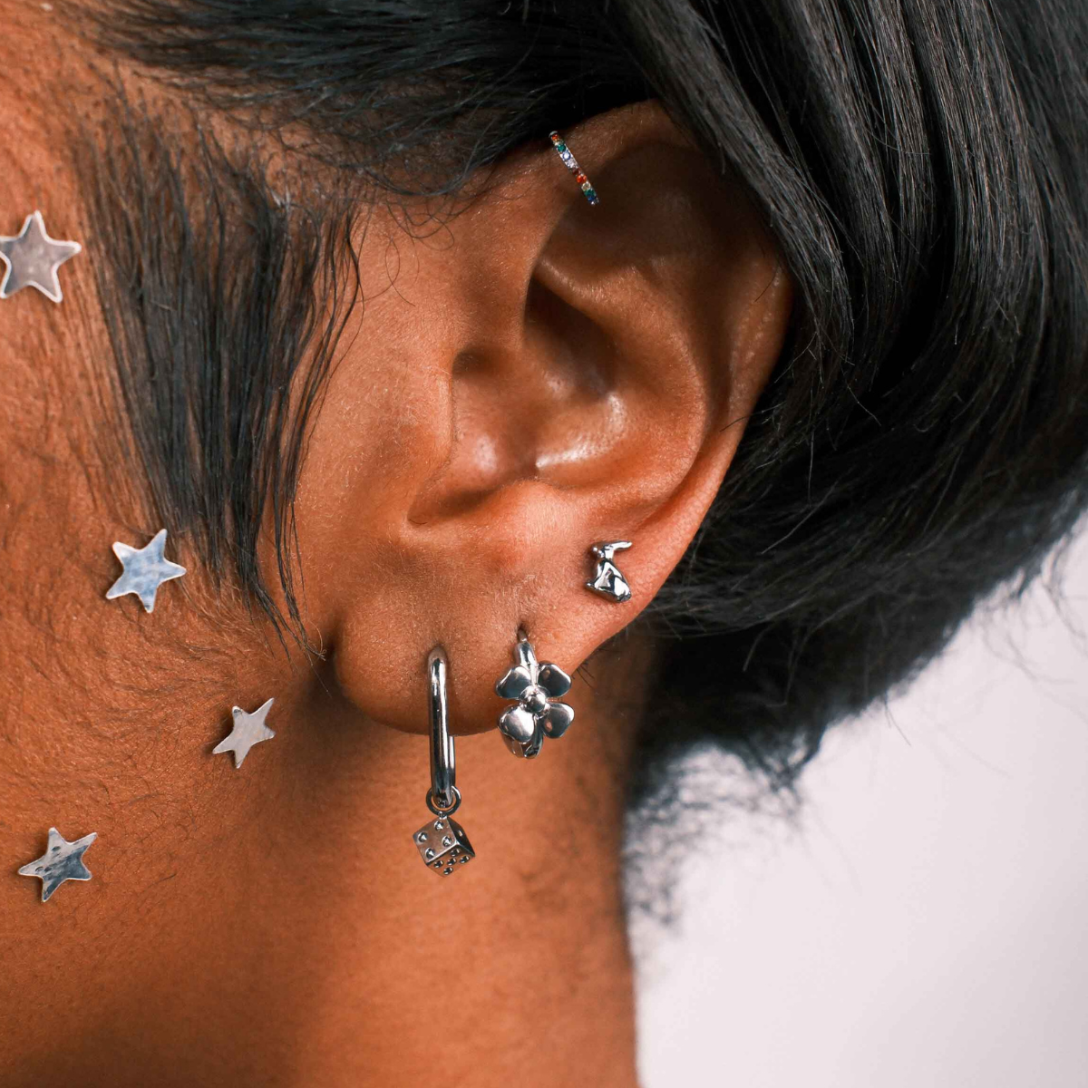 Close-up of an ear with multiple silver earrings against a blurred background