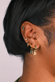 Close-up of an ear with multiple earrings on a plain background