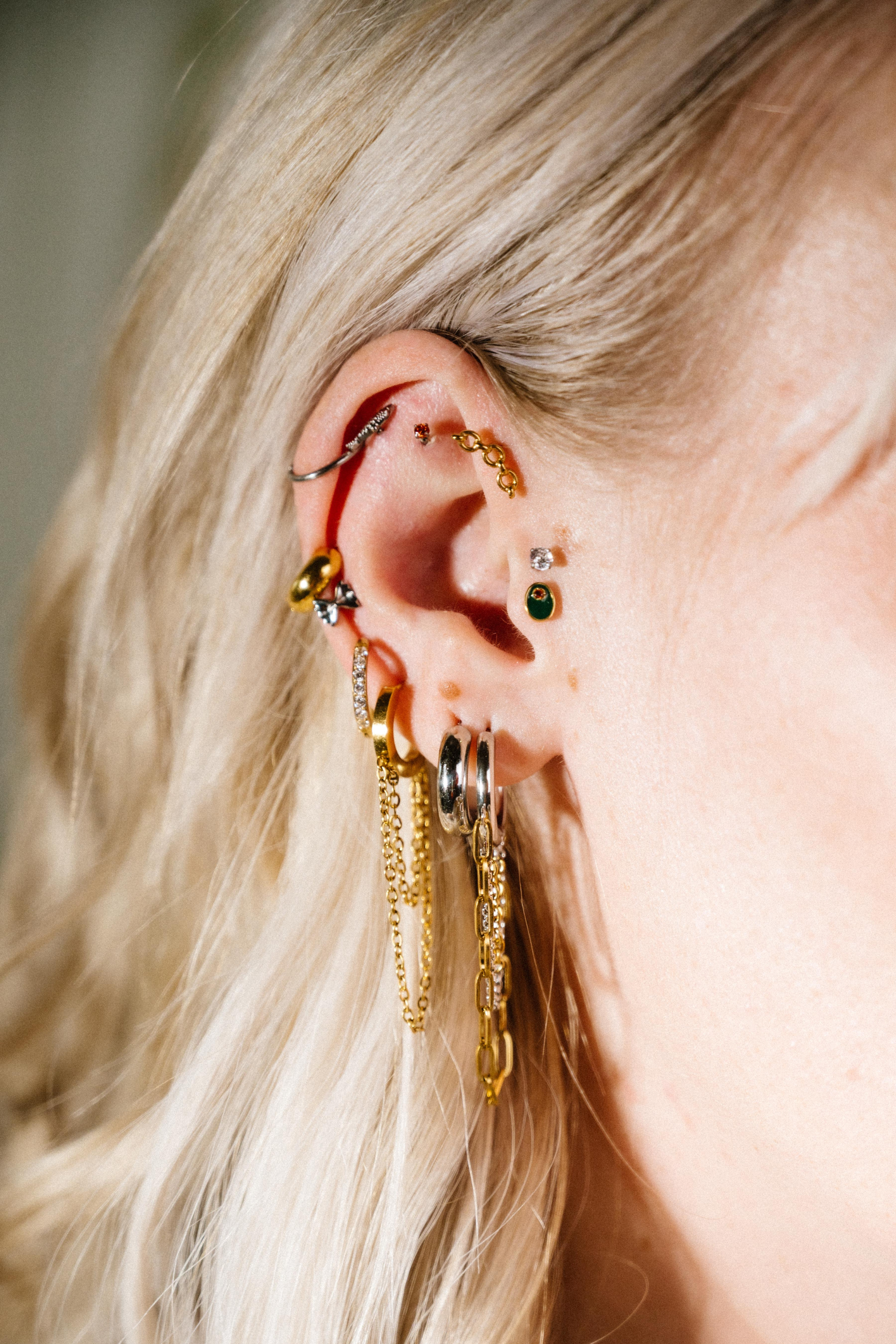 Close-up of an ear with multiple gold earrings and a blurred background