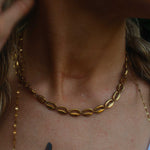 Close-up of a person wearing gold necklaces and earrings.