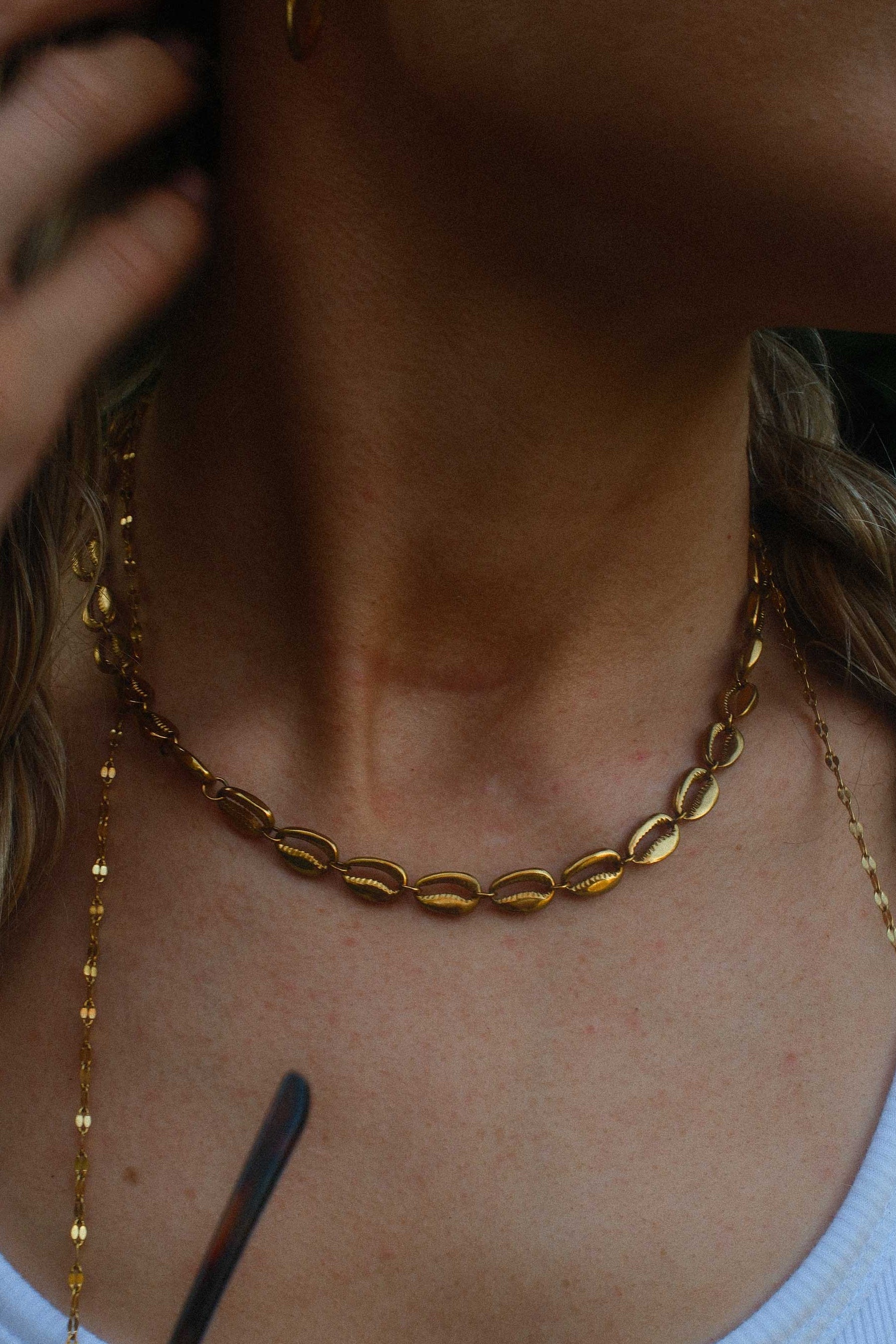 Close-up of a person wearing gold necklaces and earrings.