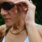Woman wearing sunglasses with a long gold chain.