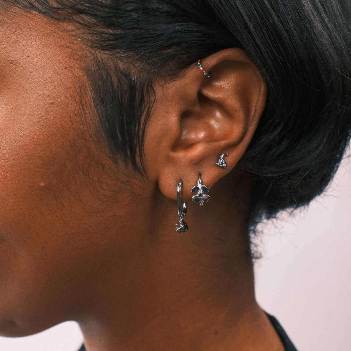 Close-up of an ear with earrings against a neutral background