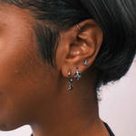Close-up of an ear with earrings against a neutral background