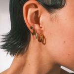 Close-up of an ear with multiple earrings against a neutral background