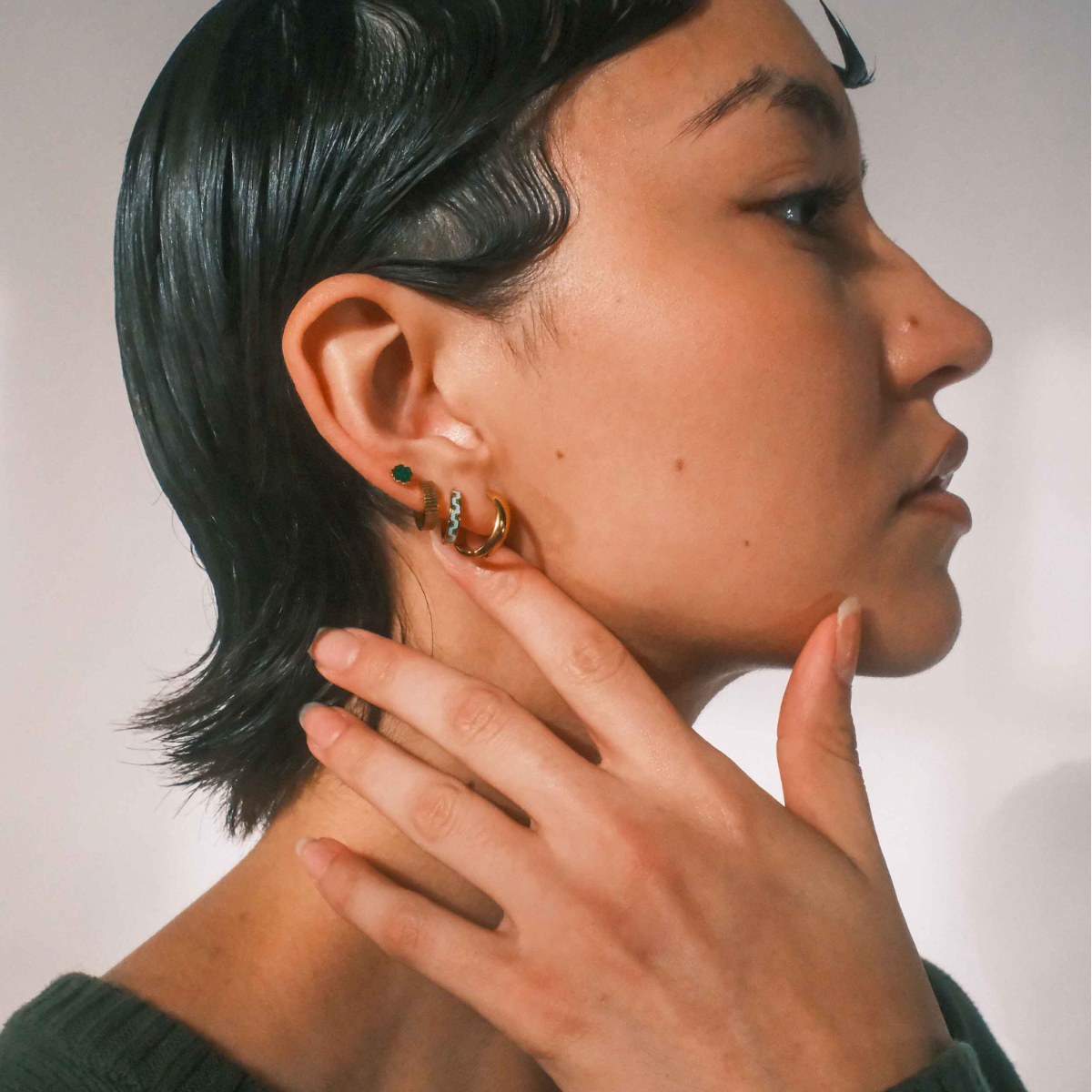 Person wearing gold hoop earrings with a neutral background