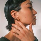 Person wearing gold hoop earrings with a neutral background