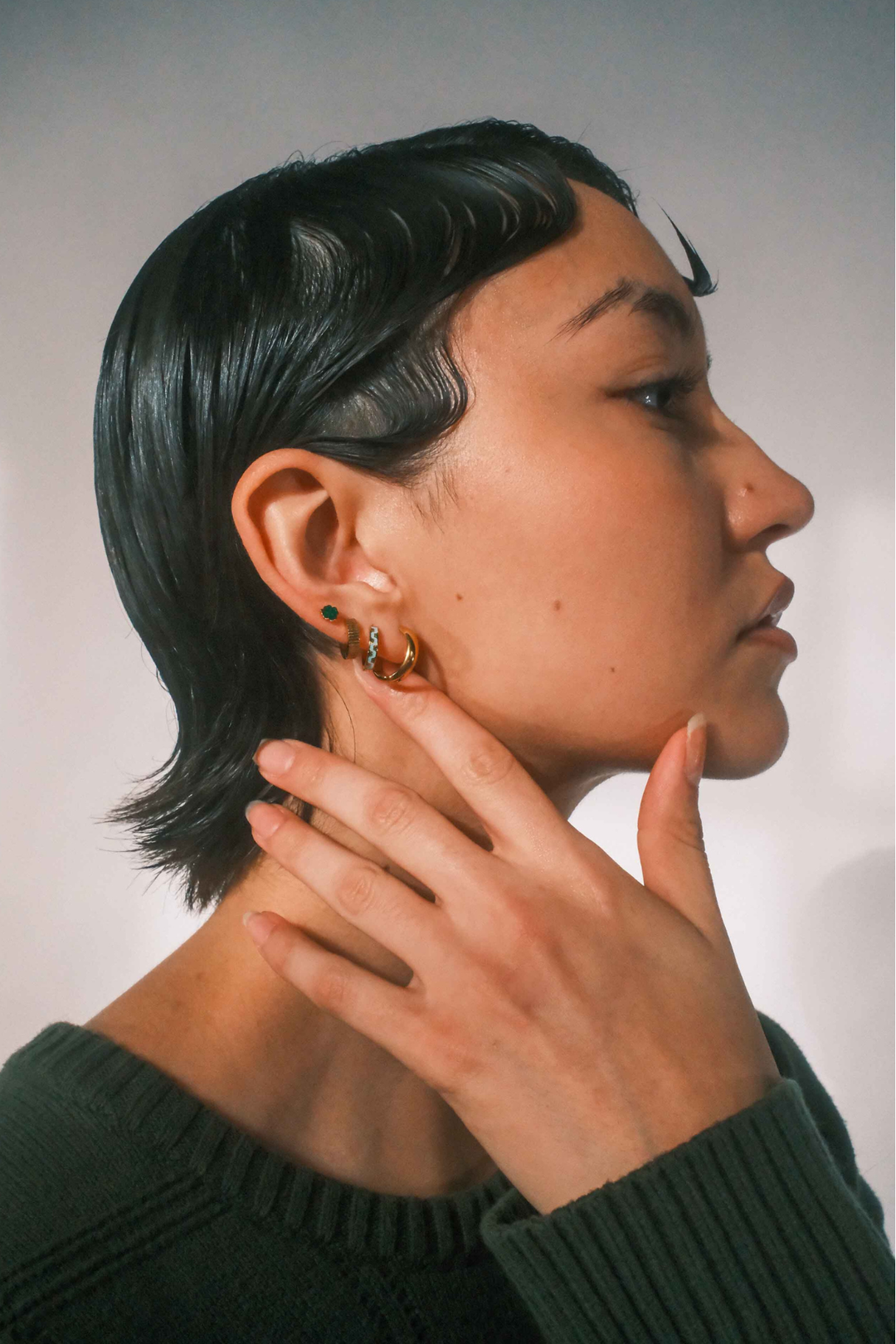 Person wearing gold hoop earrings with a neutral background