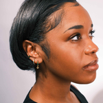 Close-up of an ear with multiple earrings on a neutral background