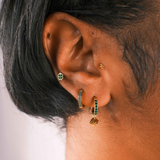 Close-up of an ear with multiple earrings on a neutral background
