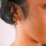 Close-up of an ear with multiple earrings on a neutral background