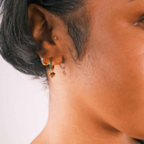 Close-up of an ear with multiple earrings on a neutral background