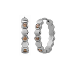 Close up of a hoop earring made from stacked hexagon shapes with a honey colored zirconia stone set into every other hexagon shape. Hoop made from 316L Surgical Steel with a honey-colored zirconia stone, set onto every other hexagon, against a blurred background.
