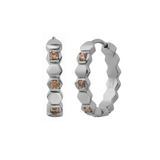 Close up of a hoop earring made from stacked hexagon shapes with a honey colored zirconia stone set into every other hexagon shape. Hoop made from 316L Surgical Steel with a honey-colored zirconia stone, set onto every other hexagon, against a blurred background.
