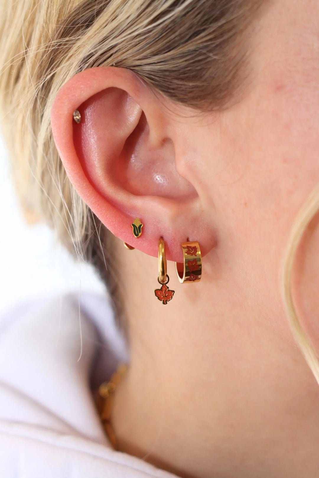 Close-up of a person wearing gold hoop earrings with heart-shaped charms.
