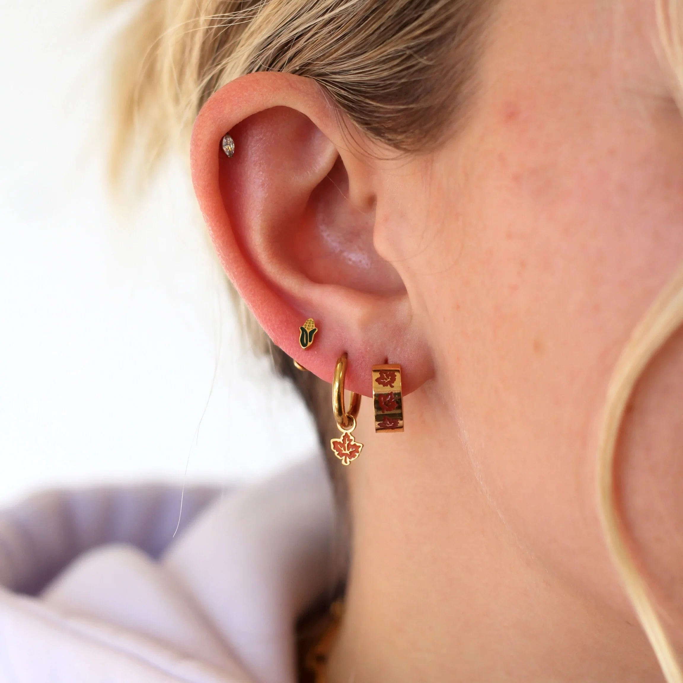 Close-up of a person wearing gold hoop earrings with a blurred background