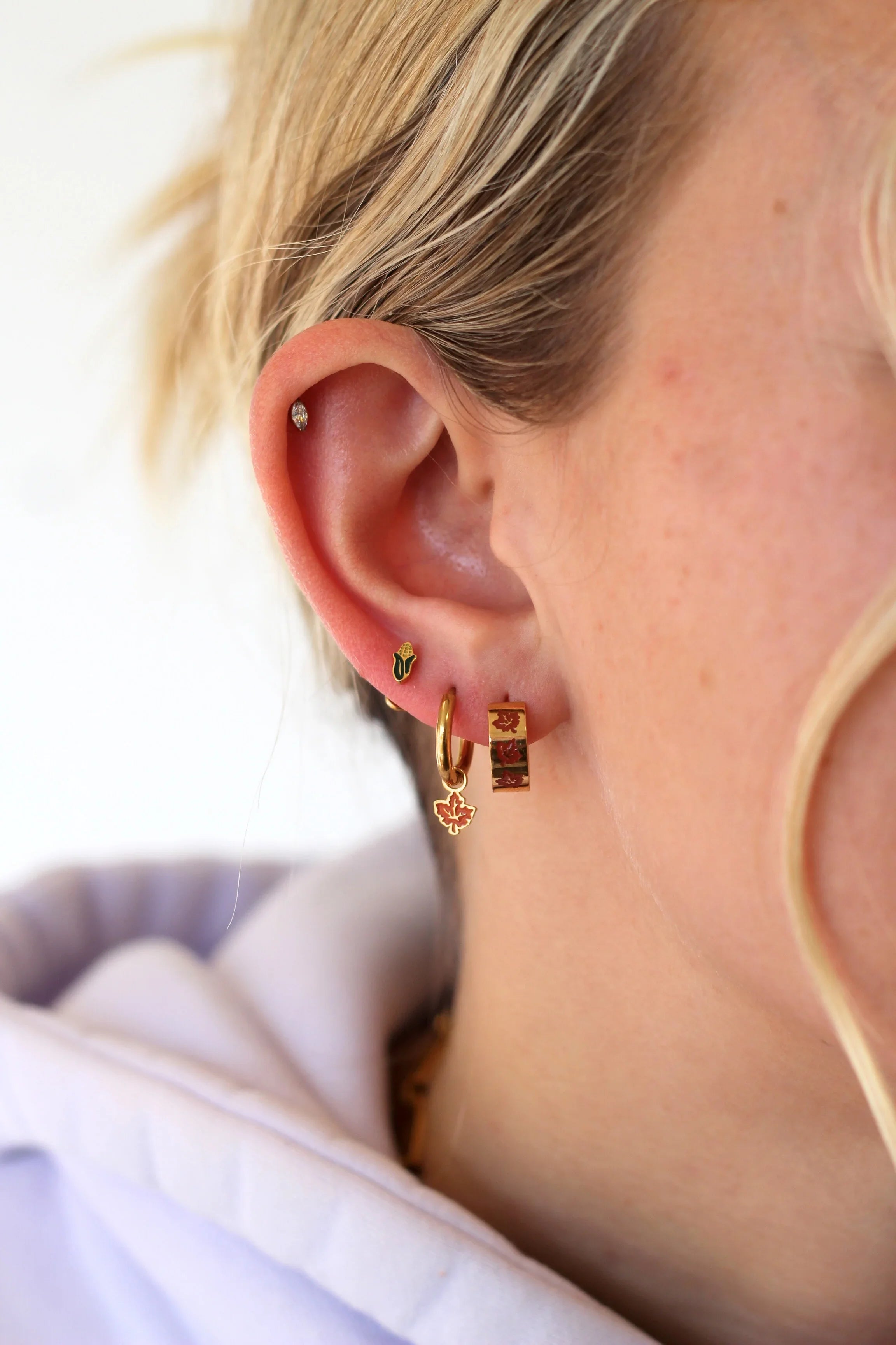 Close-up of a person wearing gold hoop earrings with a blurred background