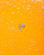 Silver earring on a bright orange background with bubbles