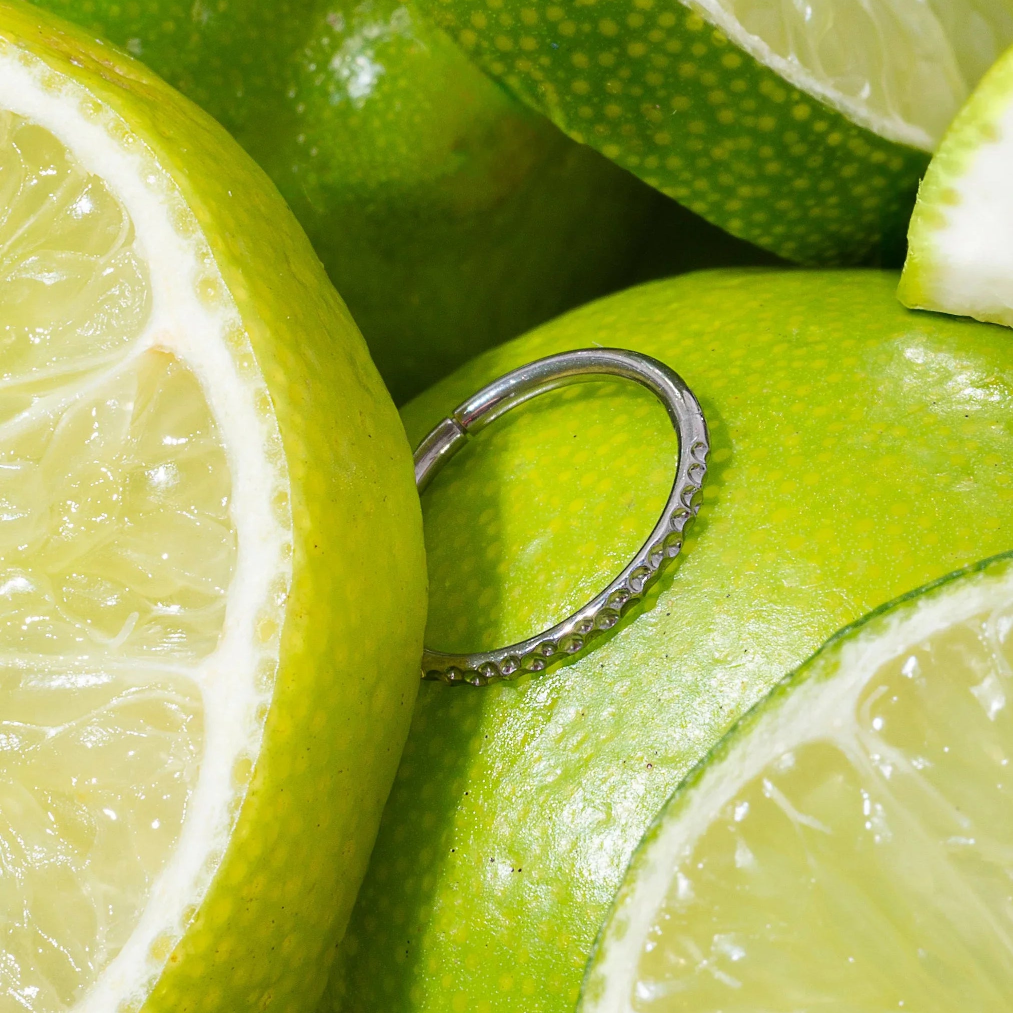 Close-up of sliced limes with a silver cartilage hoop on top