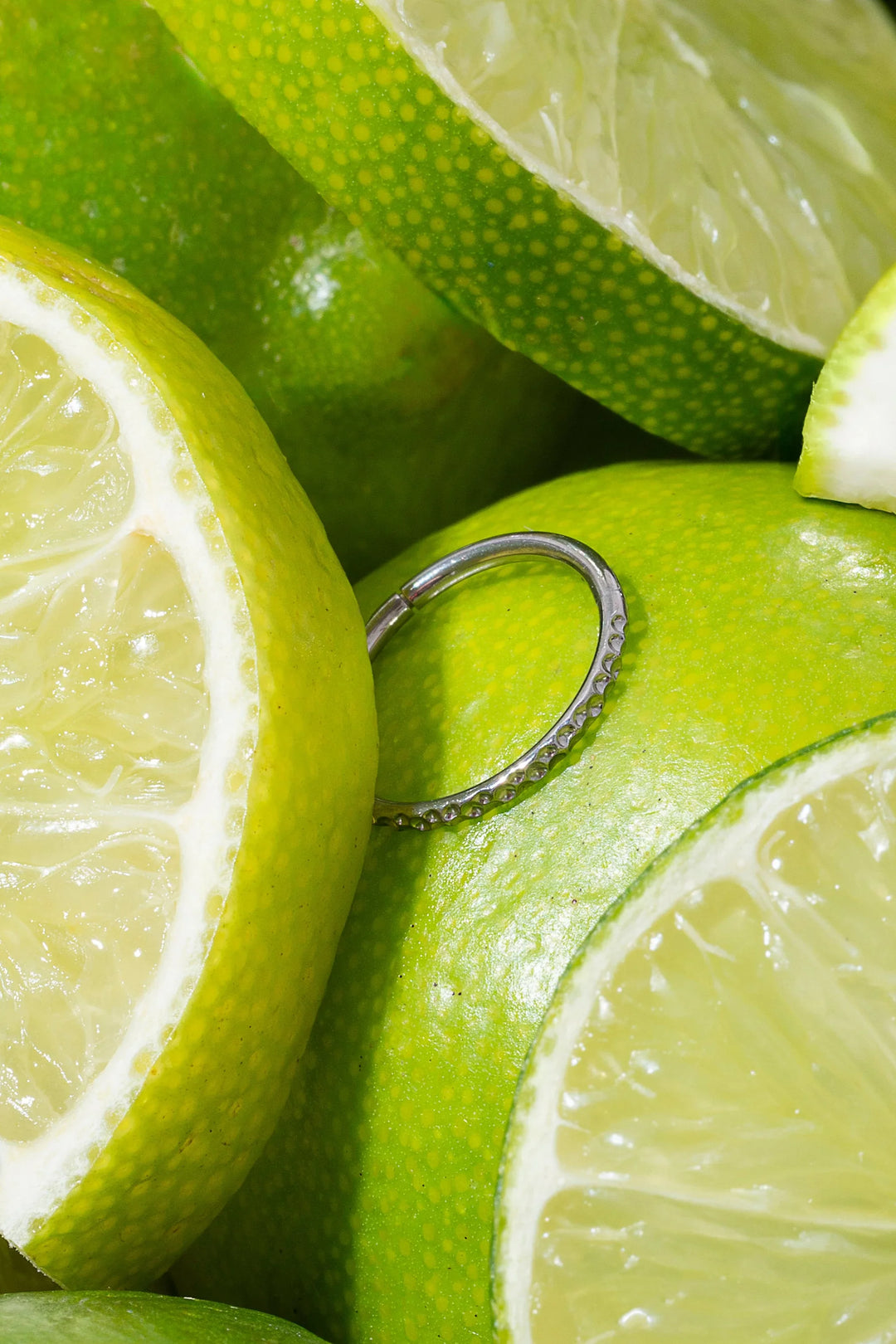 Close-up of sliced limes with a silver cartilage hoop on top