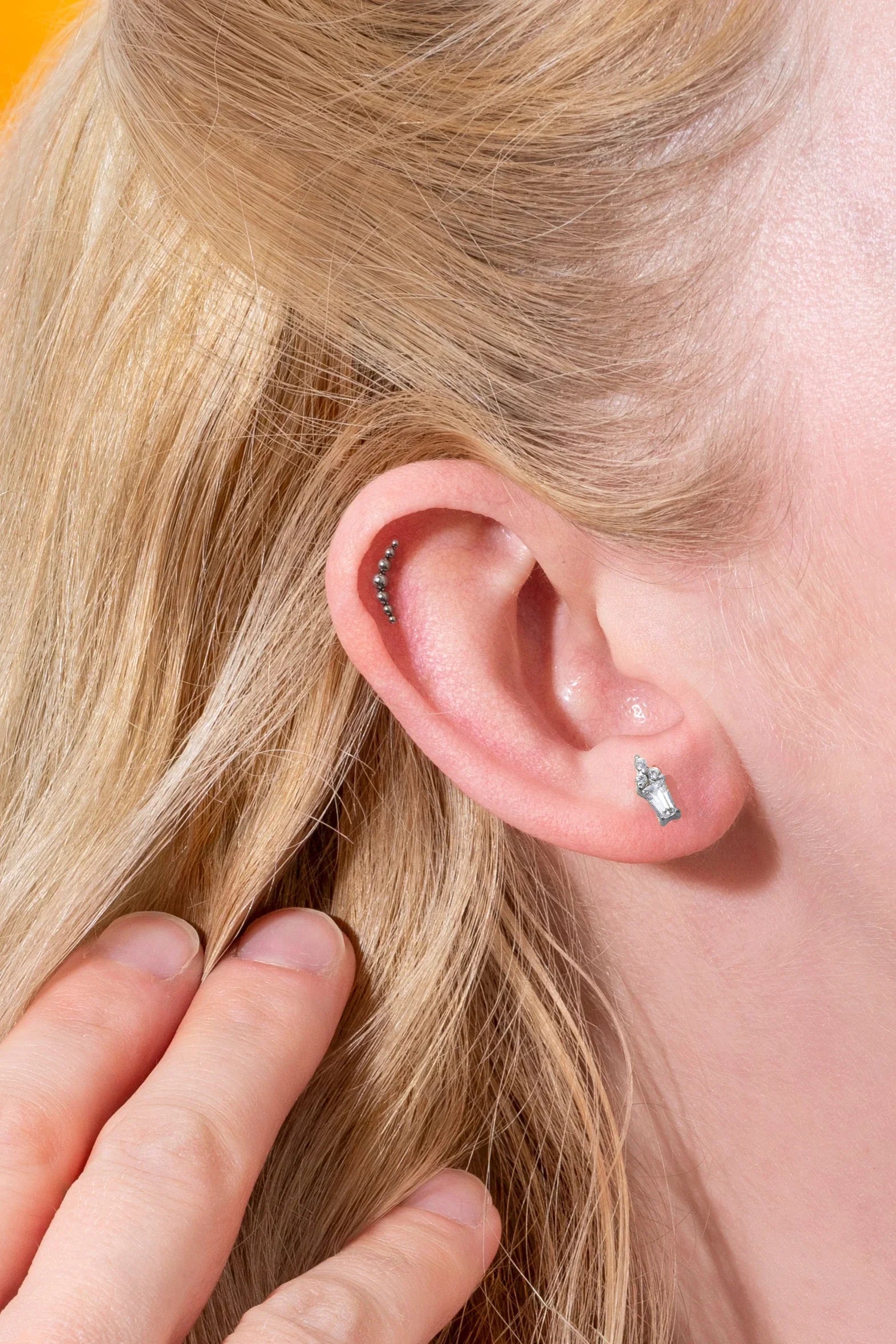 Close-up of a person's ear with earrings and blonde hair.
