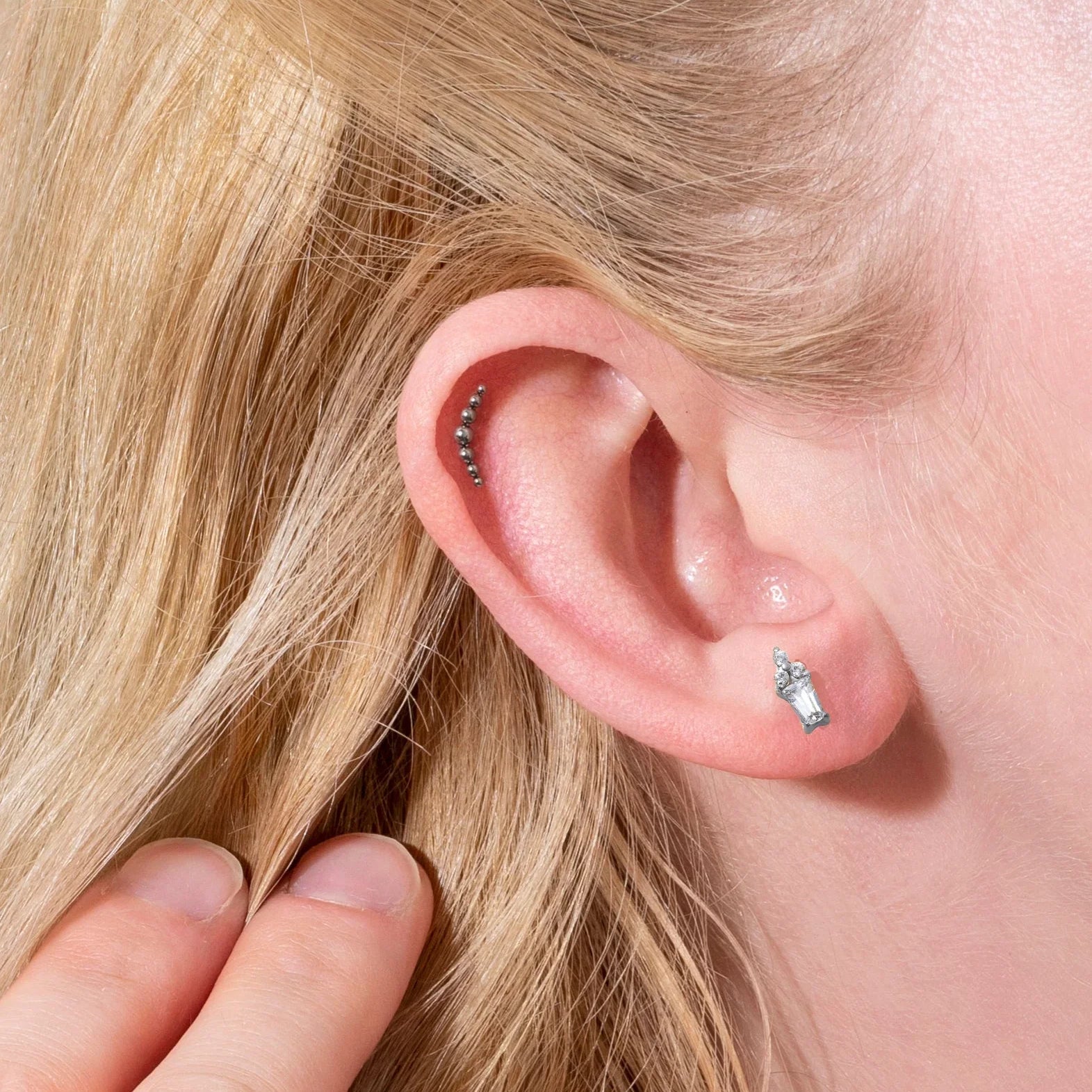 Close-up of a person's ear with earrings and blonde hair.