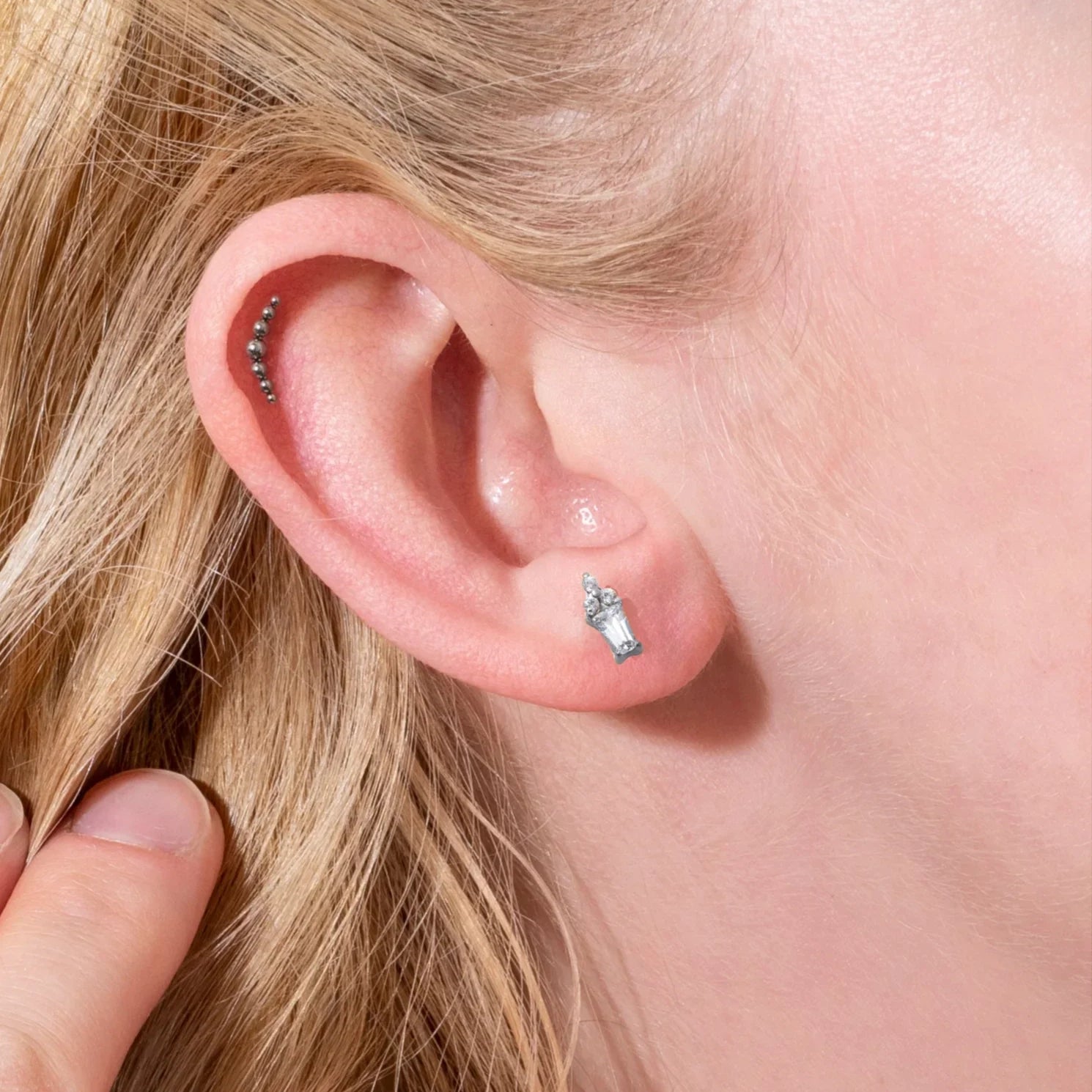 Close-up of a person's ear with earrings and blonde hair.