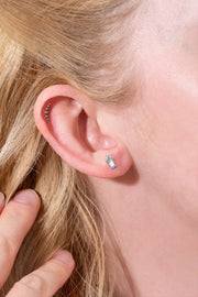 Close-up of a person's ear with earrings and blonde hair.