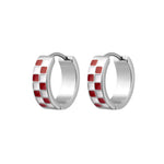 A pair of silver huggie hoop earrings with a checkered pattern of red and white enamel squares, shown on a plain white background.