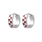 A pair of silver huggie hoop earrings with a checkered pattern of red and white enamel squares, shown on a plain white background.