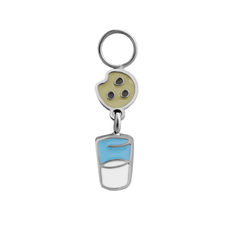 Silver enamel hoop charm resembling a chocolate chip cookie suspended over a cup of milk on a white background