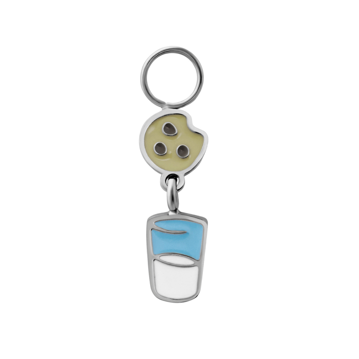 Silver enamel hoop charm resembling a chocolate chip cookie suspended over a cup of milk on a white background
